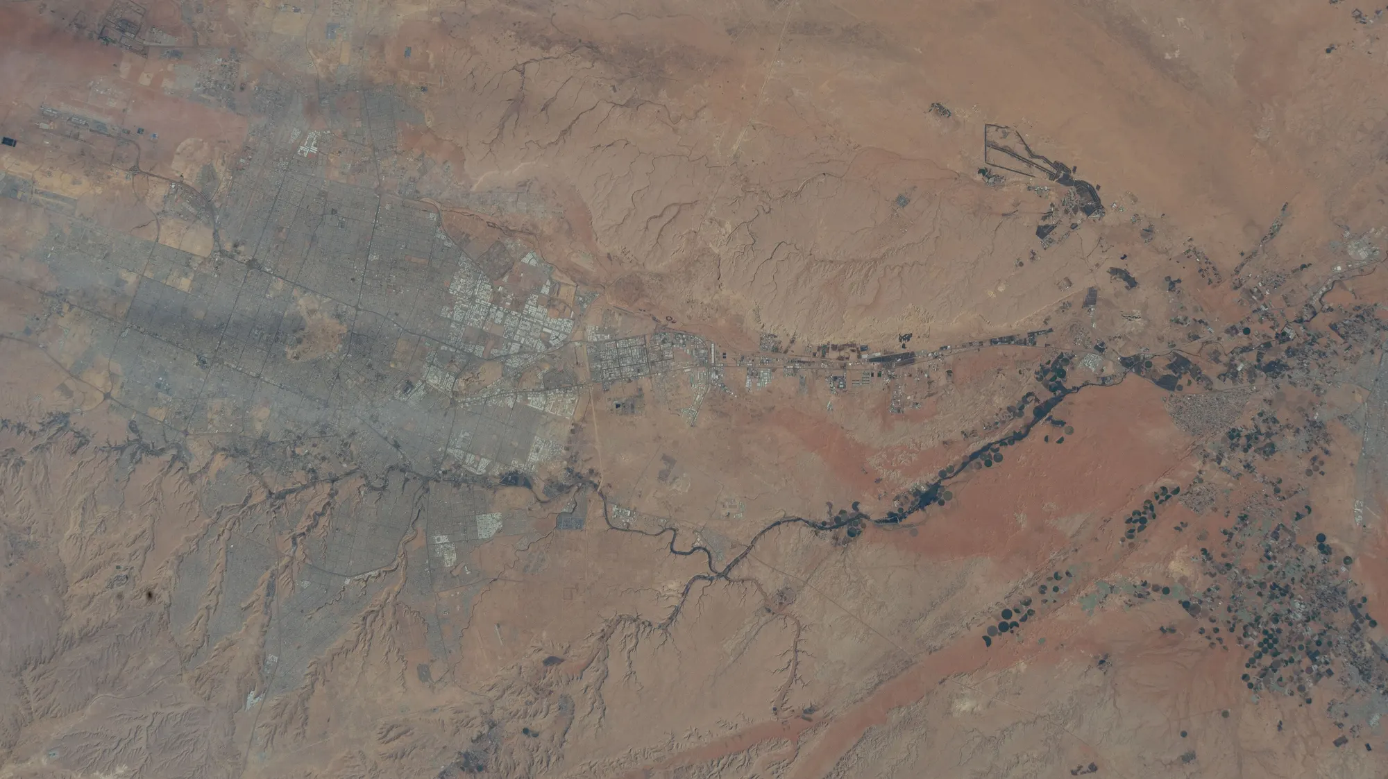 Riyadh from orbit by day: the grey city beside the winding Wadi Hanifah, in red desert
